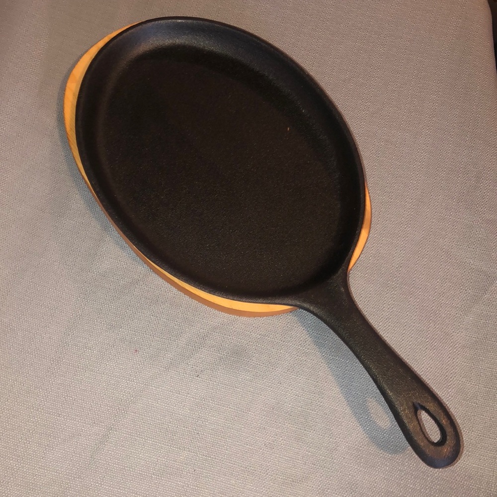 Gourmet Village cast iron skillet with wood under plate.